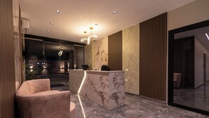 Un espace d’accueil moderne doté d’un comptoir en marbre, d’un coin salon confortable et d’une cloison en verre.