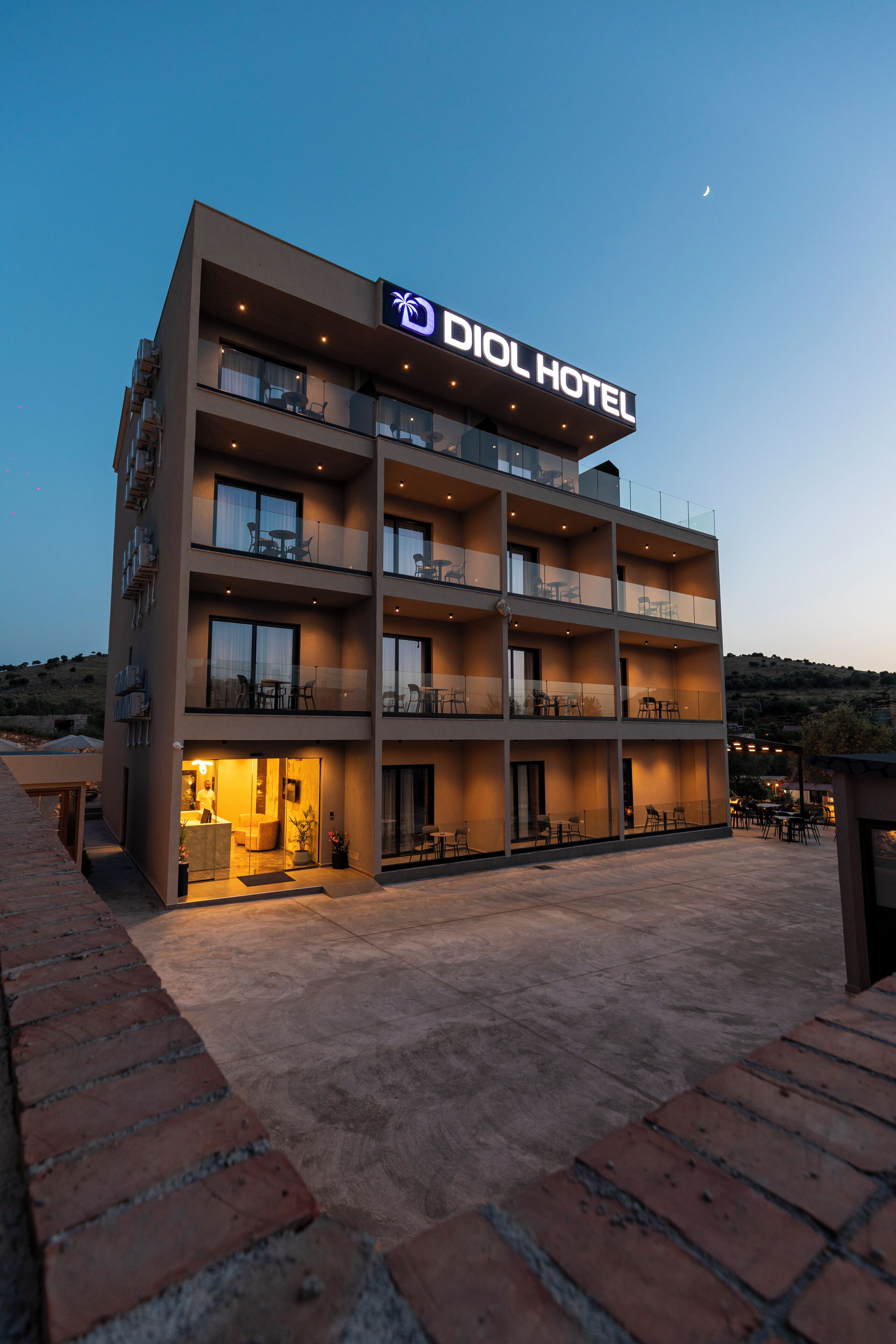 A modern hotel with multiple balconies and a well-lit entrance.