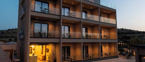 A modern hotel with multiple balconies and a well-lit entrance.