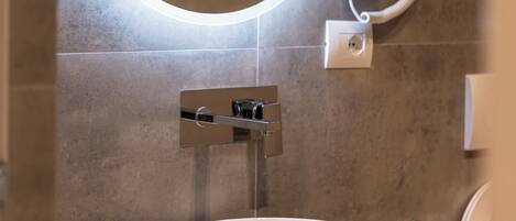 Un baño moderno con un espejo redondo, un lavabo blanco y un perchero para toallas.