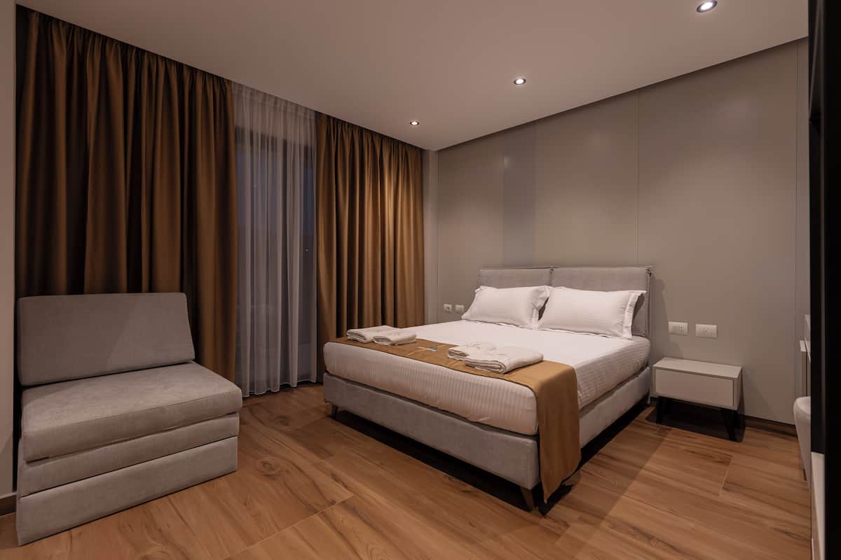 Moderni hotellihuone, jossa on suuri sänky, sohva ja pieni yöpöytä.