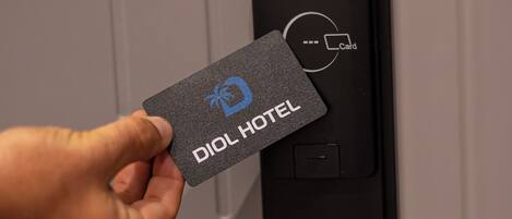 Una mano sostiene una tarjeta de DIOL HOTEL cerca de un moderno mecanismo de cierre de puerta.