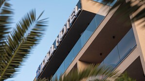 Un bâtiment moderne dont la façade est ornée d’une grande enseigne « HÔTEL », présentant un design géométrique et des fenêtres en verre réfléchissant.