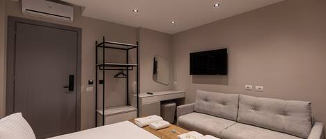 Une chambre d’hôtel moderne équipée d’un lit, d’un canapé, d’un bureau et d’une télévision.