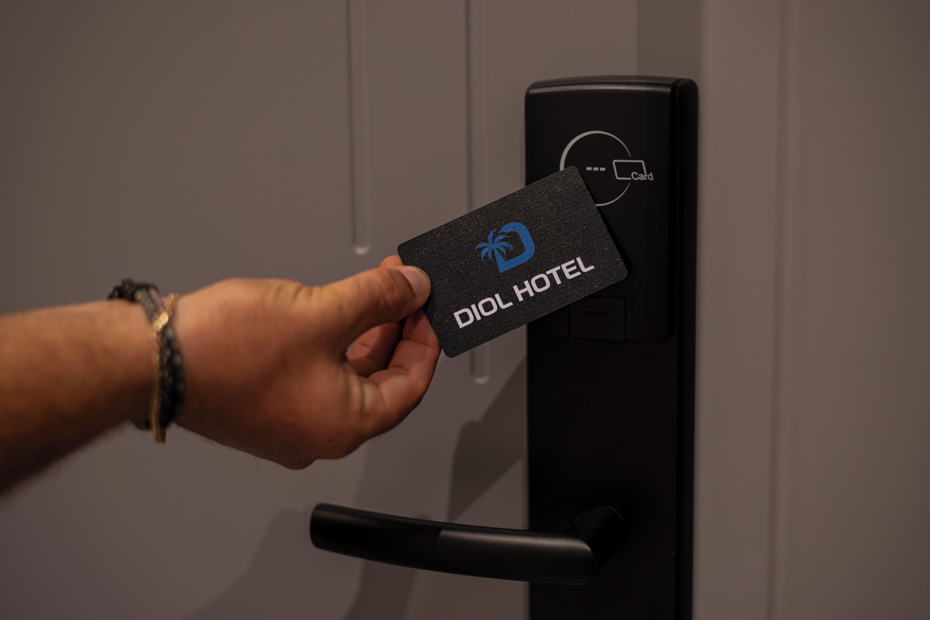 A hand holding a DIOL HOTEL card near a card reader.