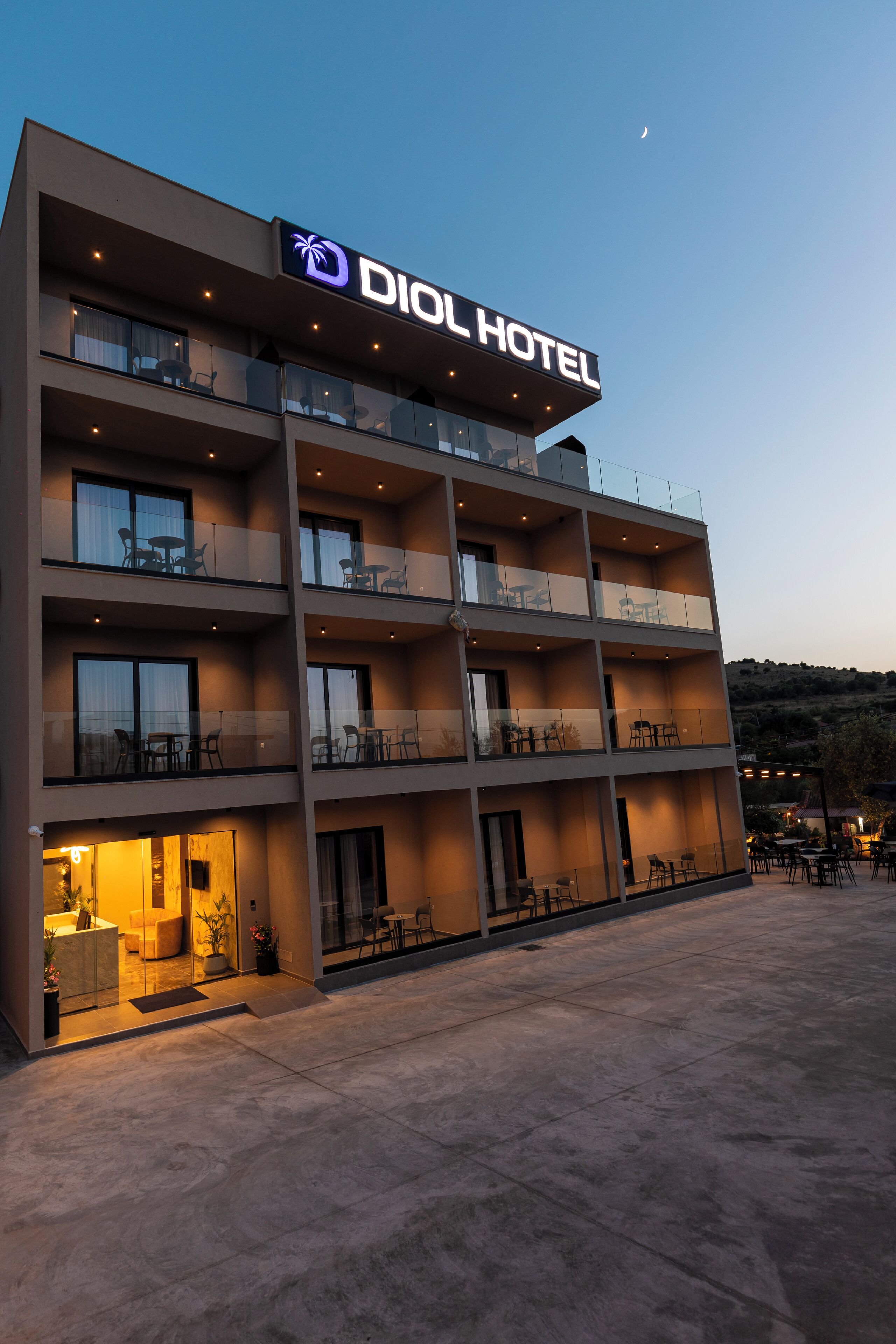 A modern hotel with a sign reading "DIOL HOTEL" and multiple balconies with outdoor seating.