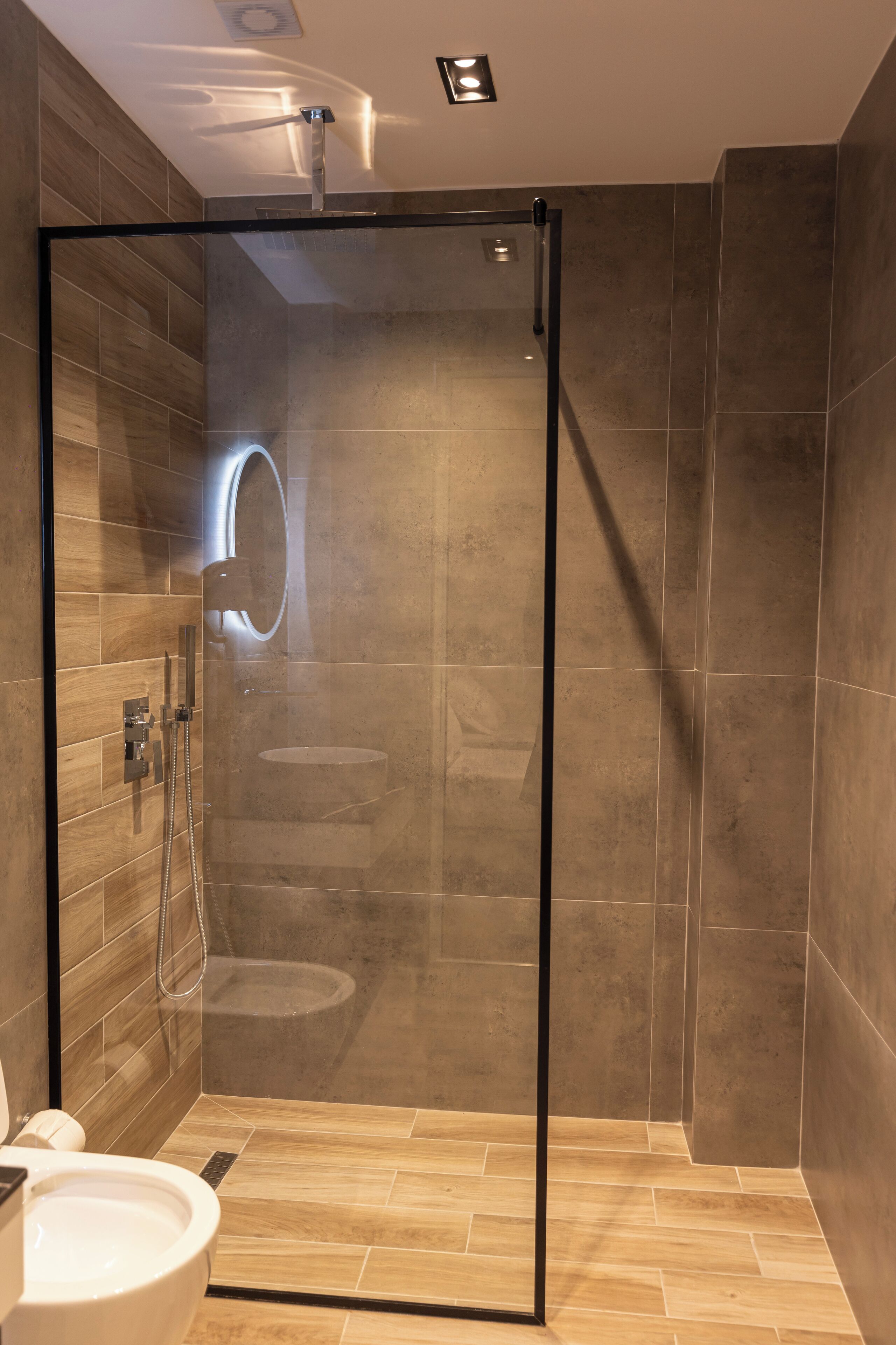 A modern bathroom with a glass-enclosed shower, a toilet, and a vanity with a mirror.