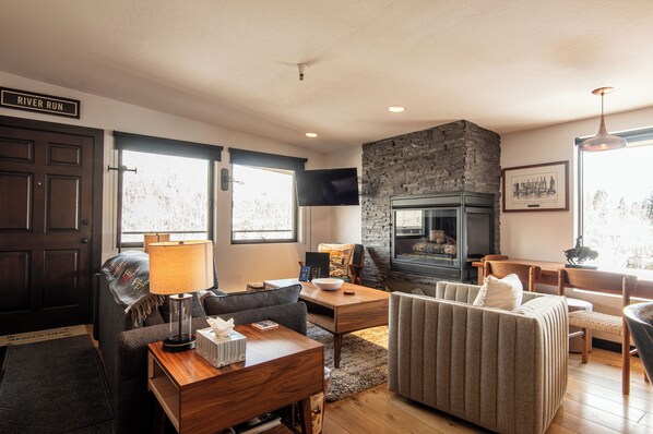 A living room with a stone fireplace, a sofa, a coffee table, and a television.