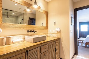 A bathroom with a wooden vanity, a large mirror, and a modern sink.