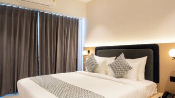Une chambre d’hôtel moderne avec un grand lit, une table de chevet avec un téléphone et un appareil de climatisation fixé au mur.