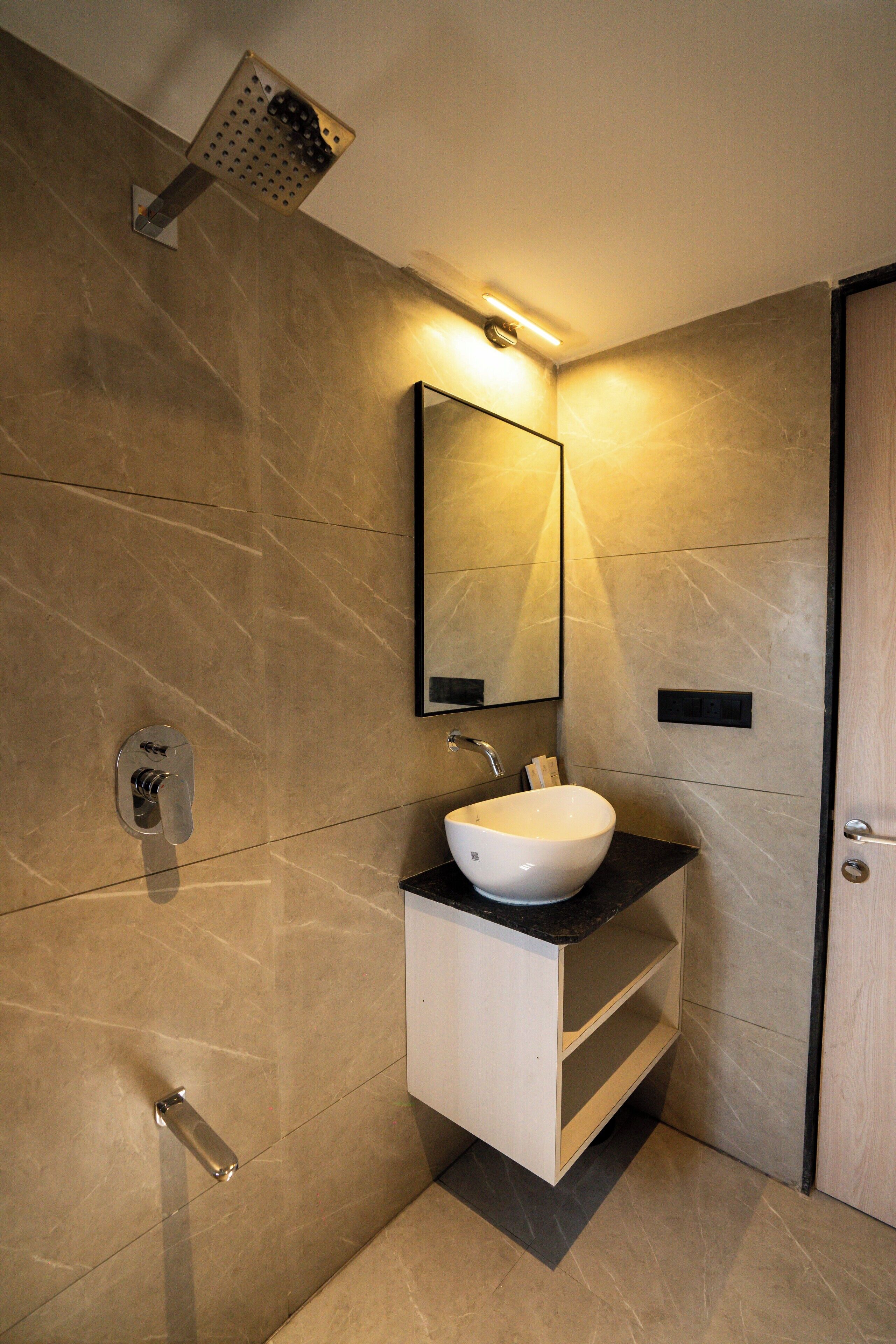 A modern bathroom with a white sink, a mirror, and a shower head.