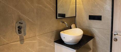 A modern bathroom with a white sink, a mirror, and a shower head.