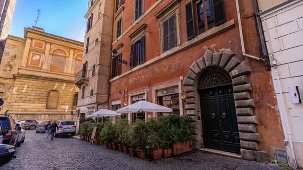 A cobblestone street with a building featuring a black door and a sign that reads "Il Gioco". - Domus Mondrian - Apartment in Central Roma (Roma)
