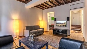 A modern living room with a sofa, a coffee table, and a television. There is a staircase leading to another level. - Domus Mondrian - Apartment in Central Roma (Roma)