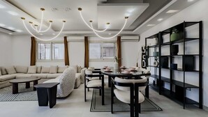 Ein modernes Wohnzimmer mit Sofa, Couchtisch, Esstisch, Stühlen und einem Bücherregal.