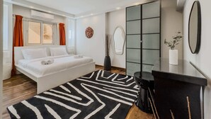 Ein modernes Schlafzimmer mit einem Bett, einem großen Spiegel, einem schwarzen Nachttisch und einer dekorativen Vase.