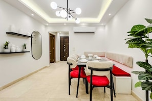 A modern dining area with a round table, red upholstered chairs, and a white sofa.