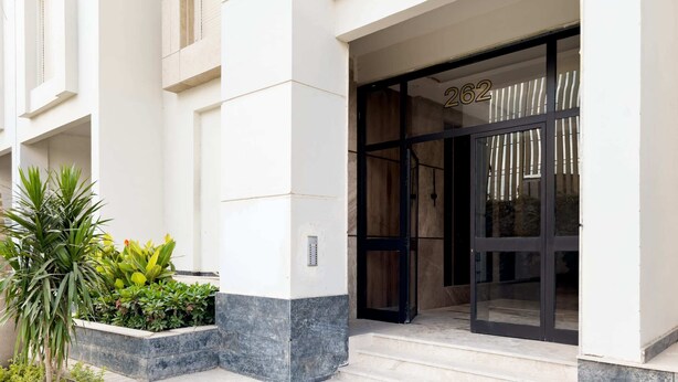 A building entrance with a glass door, number 262, and a planter with plants.