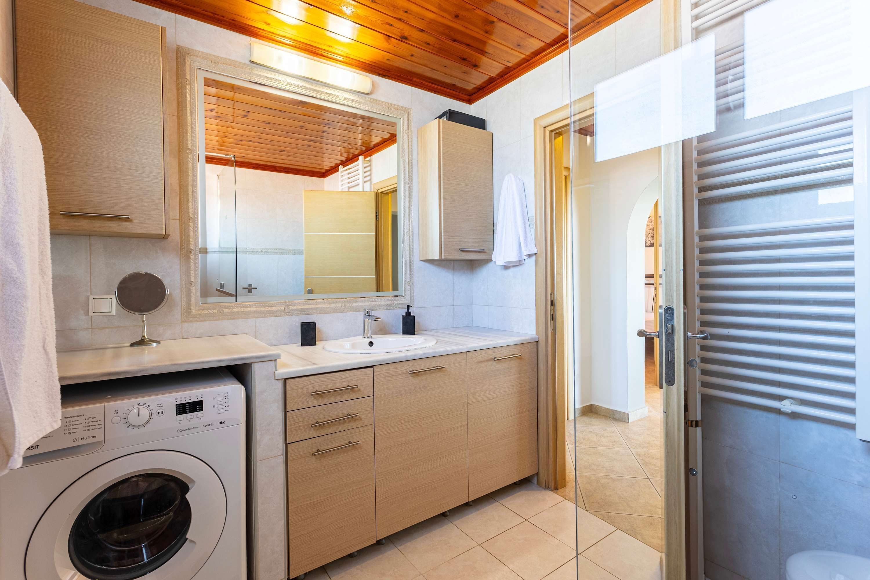 Ein modernes Badezimmer mit Waschmaschine, Waschbecken und Spiegel.