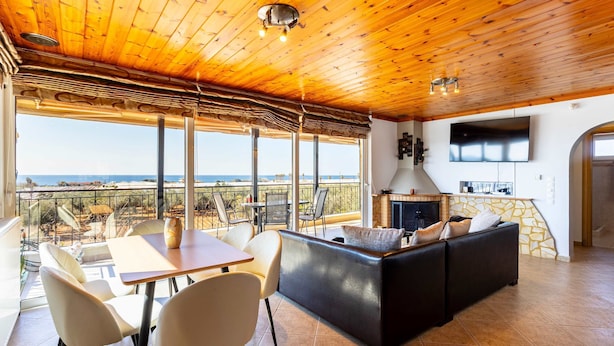 A spacious living area with a wooden ceiling, a black sofa, a dining table with chairs, and a fireplace. - Filiatra Prive Escape - Seaview Nature Serenity (Trifylia)