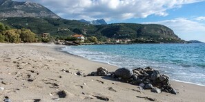 A beach with a rocky shoreline, a clear blue sea, and a mountainous backdrop. - Stara Stone House Tranquil Garden Dazzling View (West Mani)