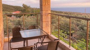A balcony with a table and chairs, overlooking a scenic landscape. - Stara Stone House Tranquil Garden Dazzling View (West Mani)