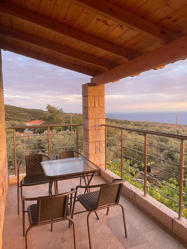 Un balcon avec une table et des chaises, donnant sur un paysage pittoresque.