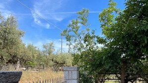 A stone pathway leading to a garden area with potted plants and a metal fence. - Stara Stone House Tranquil Garden Dazzling View (West Mani)