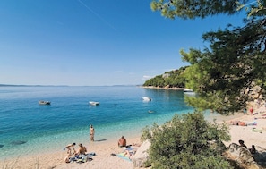 Une plage avec une eau d’un bleu limpide, des bateaux et des gens qui se détendent sur le sable.