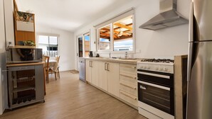 A modern kitchen with stainless steel appliances, wooden cabinets, and a dining area with a table and chairs.