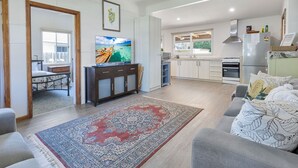 A spacious living room with a large rug, a sofa, and a television.