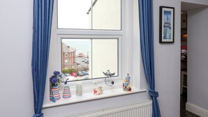 A room with a large window, a radiator below, and a shelf with decorative items.