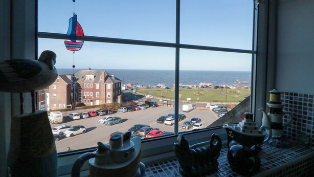 A view from a window with a view of the sea and a parking lot.