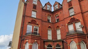A red brick building with multiple windows and a corner balcony.