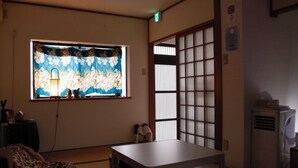 Una habitación japonesa tradicional con suelo de tatami, pantalla shoji, una mesa y un futón.