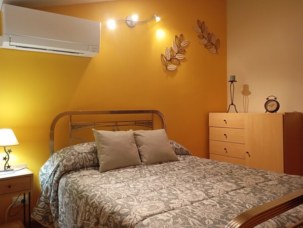 A bedroom with a bed, bedside table, lamp, dresser, and wall decorations. - CASA RURAL LA CORNEJA (Huermeces del Cerro)