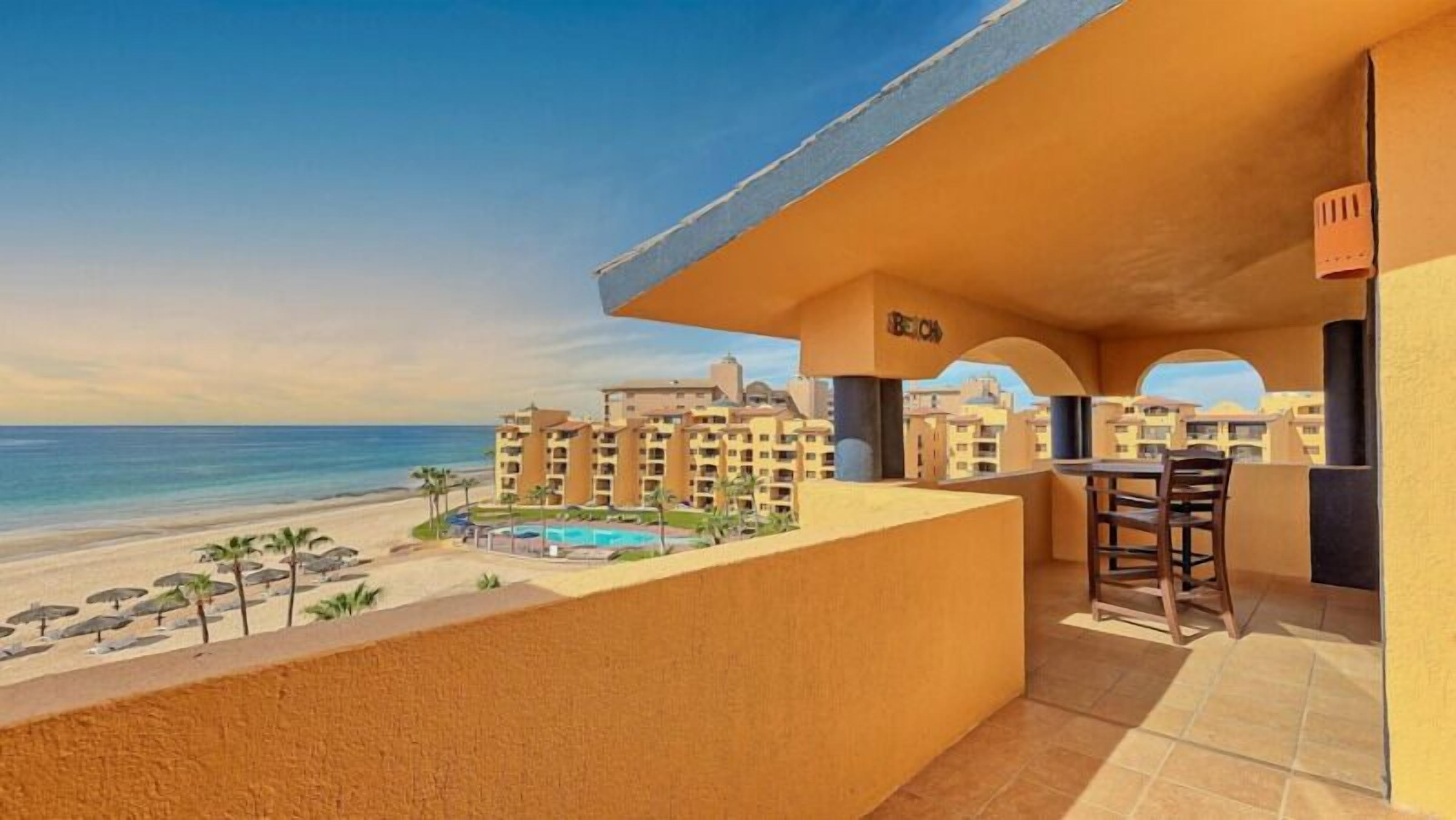 A balcony with a view of the beach and pool, featuring a bar area and multiple balconies.