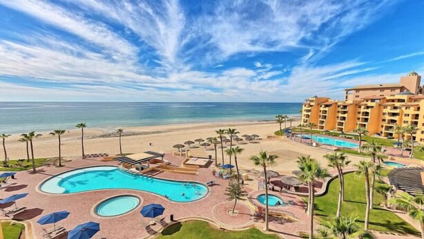 A resort with a large pool area, beach access, and a hotel building with multiple balconies. - BeachBumCondos (Puerto Peñasco)