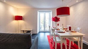 A modern dining area with a white table set for four, red accents, and a red pendant light.