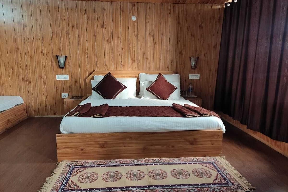 Puupaneloitu makuuhuone, jossa on suuri sänky, kaksi yöpöytää ja kuviollinen matto.