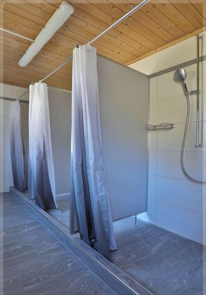 Une salle de bain moderne avec une douche, un luminaire au plafond et un carrelage au sol.
