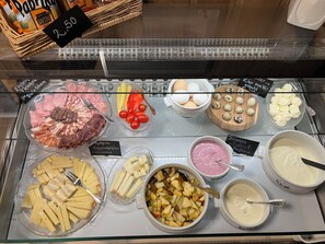 Un présentoir de charcuterie proposant une variété de fromages, de viandes et de condiments.