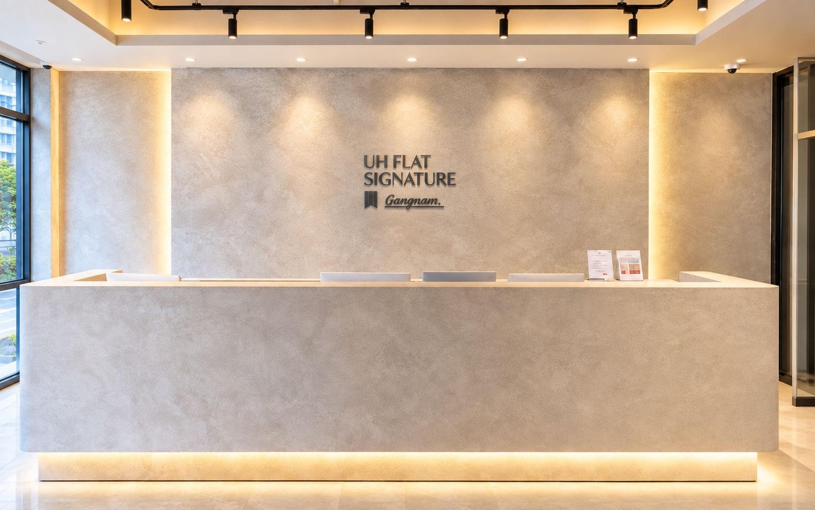 A reception desk with a sign reading 'UH FLAT SIGNATURE Ganam.'