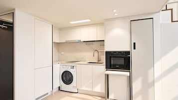A modern kitchen with built-in appliances, a washing machine, and a compact refrigerator.