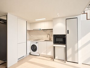 A modern kitchen with built-in appliances, a washing machine, and a compact refrigerator. - UH FLAT SIGNATURE GANGNAM (Seoul)