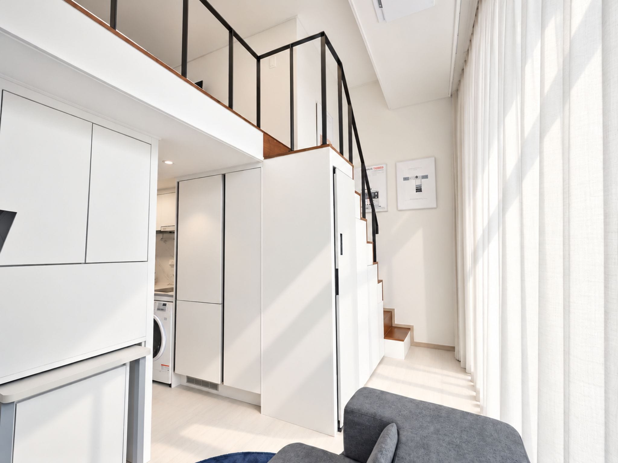 A modern apartment with a kitchen, a dining area, and a living room with a sofa.