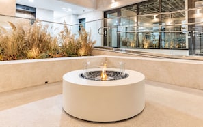 Un moderno hogar exterior con cerramiento de vidrio, rodeado por una jardinera de concreto con pastos altos.