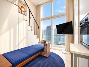 A modern room with a bed, a TV, a small table, and a window with a city view. - UH FLAT SIGNATURE GANGNAM (Seoul)