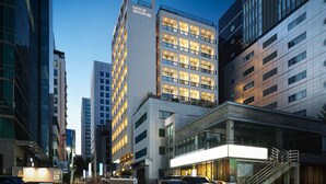 A modern hotel with multiple floors, large windows, and a prominent sign. - UH FLAT SIGNATURE GANGNAM (Seoul)