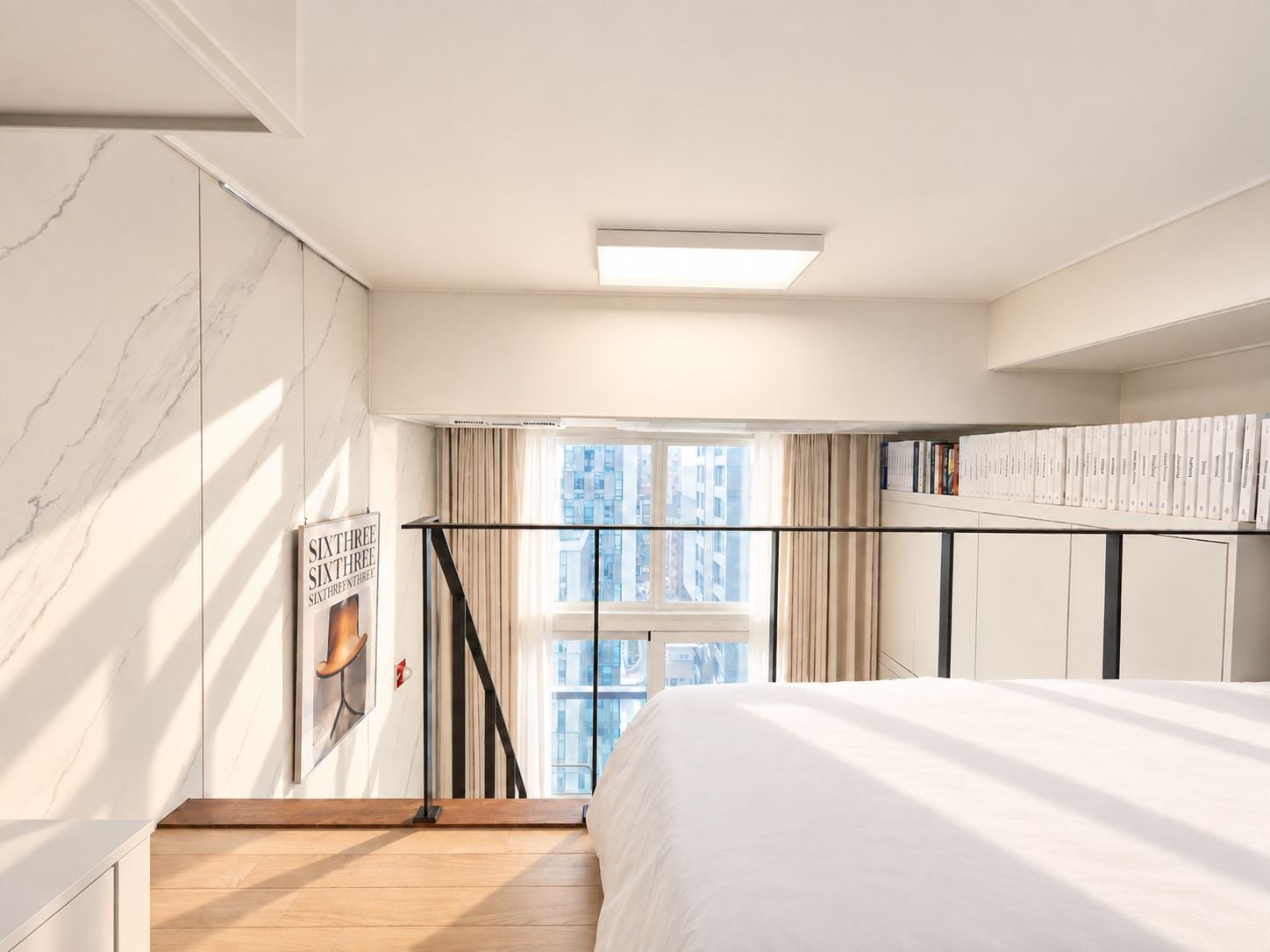 A bedroom with a bed, a bookshelf, a window with curtains, and a view of buildings outside.
